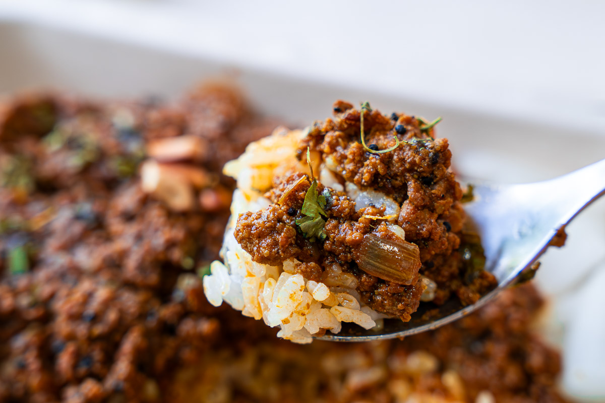 ナッツとアチャール（タマネギ）が添えられたキーマカレーの実食シーン